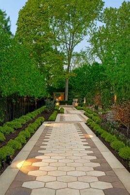 Beautiful landscaped garden pathway with hexagonal tiles, lush greenery, and decorative gazebo.